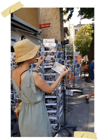 Une personne avec chapeu qui regarde les cartes pastales du village