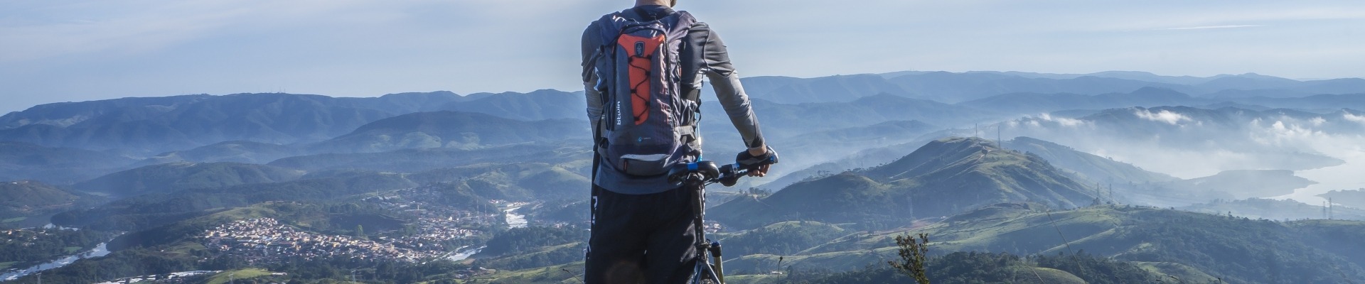 Biker Holding Mountain Bike Au Sommet De La Montagne Avec De L'herbe Verte